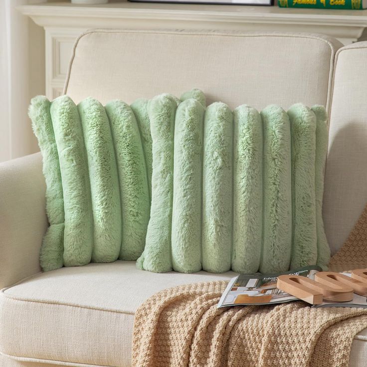 a white couch with green pillows on it and a wooden tray next to the chair