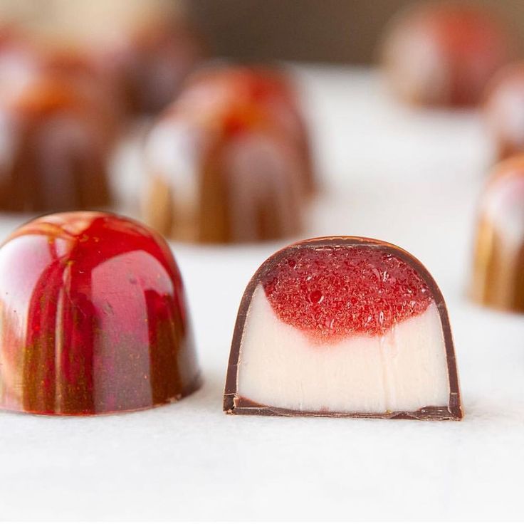 some kind of dessert with red and white icing on it's side, sitting next to each other