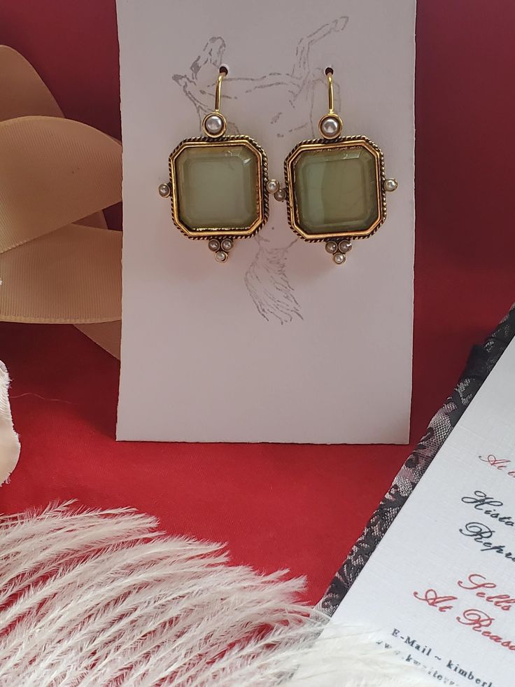 I saw these earrings and knew they were perfect to offer in the shop.  They are gold plated earwires with a square glass green intaglio and pearl elements.  Perfect to wear for late 18th century, early 19th century on up to today.  I love them! They measure 1-1/4 inches long by just over 1/2 inch wide.  The earwire is super long which is good to stay in the ear. Lots of inspiration on my Pinterest page.  https://www.pinterest.com/kkwalte/_saved/ Gold Rectangular Earrings For Gift, Square Pendant Earrings For Gift, Gift Square Pendant Earrings For Pierced Ears, Gift Earrings With Square Pendant For Pierced Ears, Elegant Nickel-free Square Pendant Jewelry, Elegant Square Pendant Earrings As Gift, Elegant Square Nickel-free Earrings, Elegant Antique Gold Jewelry For Party, Elegant Antique Gold Party Jewelry