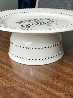 a white cake plate sitting on top of a wooden table