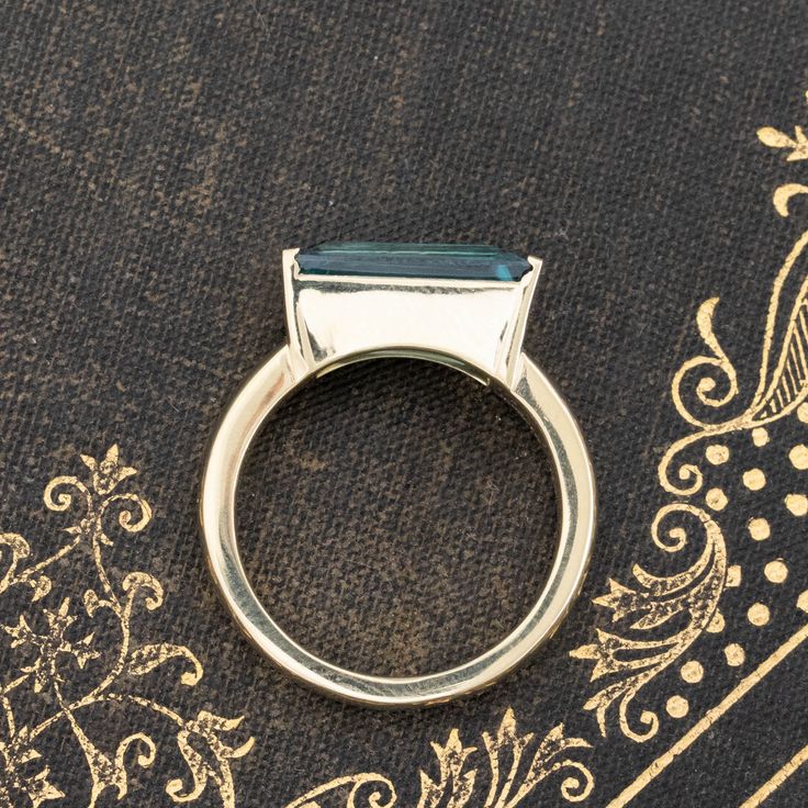 This is probably our favorite way to set a tapered baguette-shaped gemstone! An equally tapered ring setting, which follows the width of the stone that sits in the center. We find it to be so charming, so unique and incredibly elegant on the finger. The baguette has gorgeous spread across the top of one's finger, especially in this delicious blue shade. This aquamarine is crisp and chunky in the best way - the color combo of blue and yellow is also to die for! 18kt yellow gold Size 6 & resizable Modern Baguette Cut Topaz Promise Ring, Modern Blue Baguette Cut Emerald Ring, Modern Baguette Cut Sapphire Ring For Anniversary, Modern Emerald Baguette Cut Ring, Modern Emerald Cut Sapphire Ring With Accent Stones, Luxury Blue Topaz Baguette Cut Rings, Gift Sapphire Ring With Baguette Cut And Accent Stones, Fine Jewelry Solitaire Baguette Cut Sapphire Ring, Fine Jewelry Solitaire Sapphire Ring With Baguette Cut