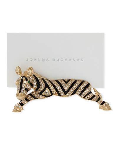 an animal brooch with black and white stripes on it's body, sitting next to a card