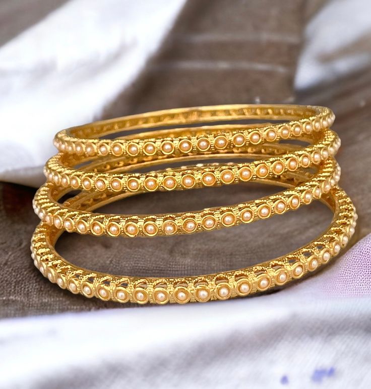 Indian gold pearl bangle set of 4. This beautiful gold finish bangles are made up of brass with embedded pearl details. Add this bangles to your chuda or wear it alone to get minimalistic look for any occasion.   All orders Ship same day if placed before 4:00 PM EST  Create beautiful memory for any occasion with elegant jewelry for your loved ones We will be happy to navigate you through the process so if you have any questions regarding our product before placing an order reach out to us and we Elegant Stackable Bangle For Festivals, Festival Stackable Bangles, Festival Stackable Bangle, Traditional Gold Pearl Bracelet For Festivals, Festive Gold Pearl Bracelet For Weddings, Elegant Bangle For Diwali Celebration, Festive Gold Pearl Wedding Bracelet, Festive Wedding Gold Pearl Bracelet, Traditional Gold Bangle Pearl Bracelet