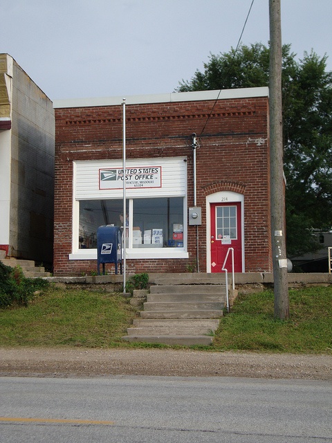 an old brick building with stairs leading up to the front door and steps down to the sidewalk