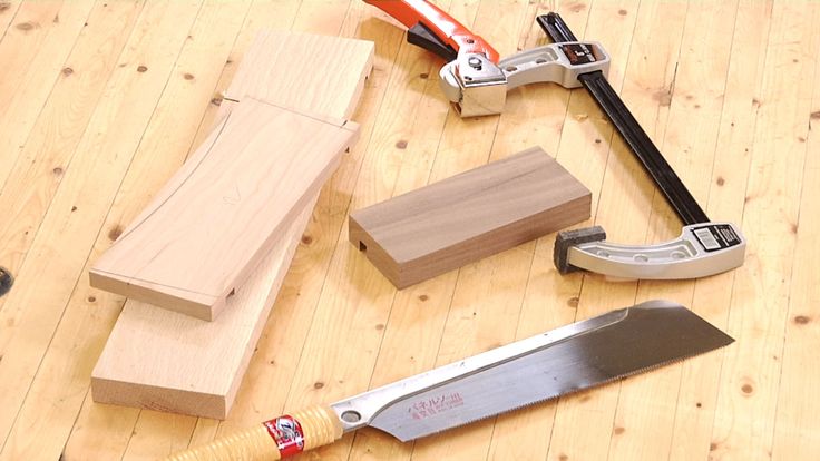 some tools are laying out on a wooden table with one knife and the other wood block