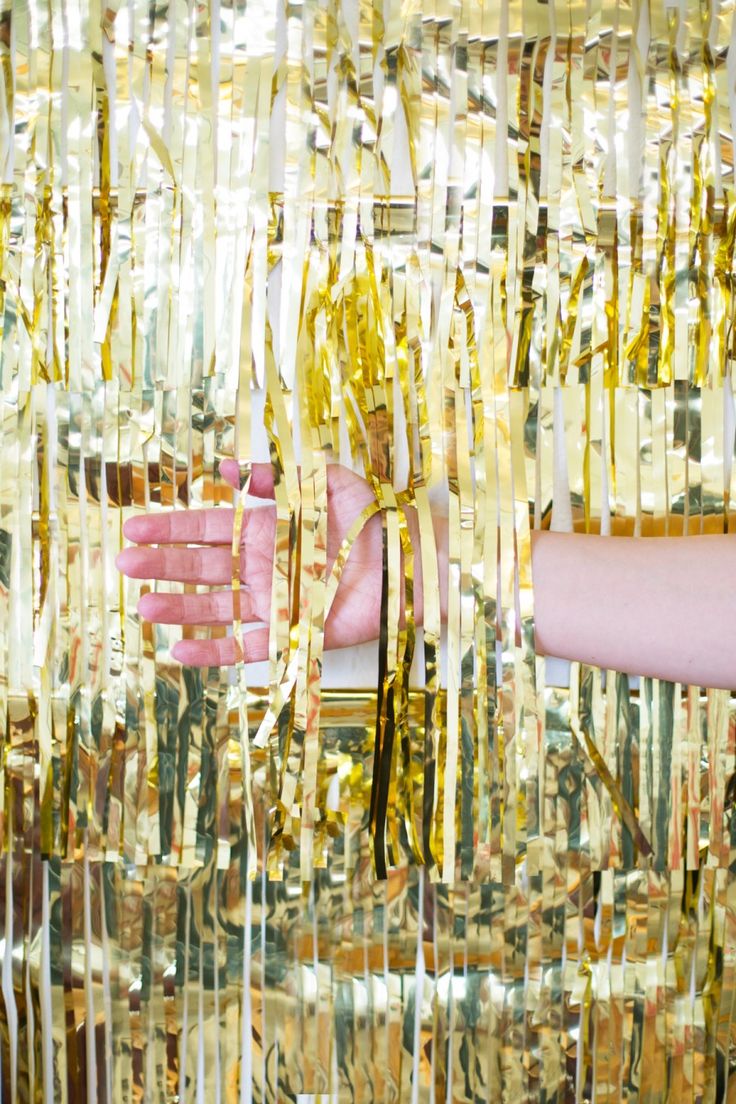 a woman's hand reaching for a gold curtain