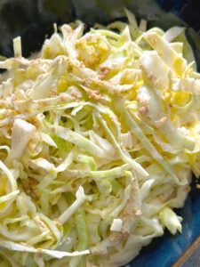 a blue bowl filled with coleslaw on top of a wooden table