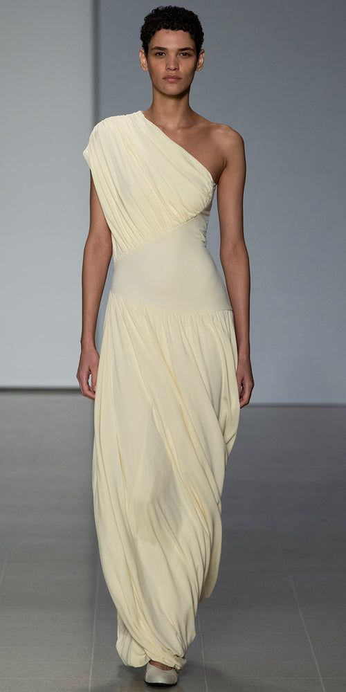 The Ugbad Dress with its one shoulder design and thoughtfully placed asymmetric basque is crafted in sustainable Italian crepe viscose jersey with beautiful weight and drape. Fully lined, the hemline features our signature twisted “bubble” design and finishes at the ankle.  In a soft buttermilk hue, this is a standout Draped Jersey Dress, One Shoulder Dress Outfit, Archive Dress, Draped Fashion, Dresses Runway, Draping Dress, Yellow Outfits, Mary Dress, Formal Chic