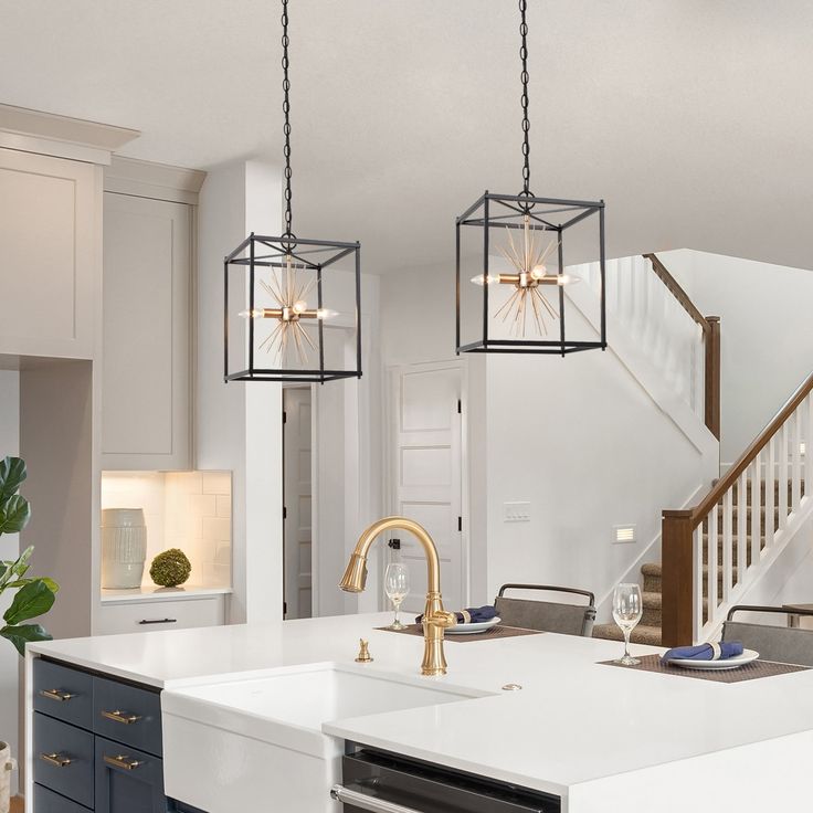 a kitchen with two hanging lights over the sink and an island in front of it