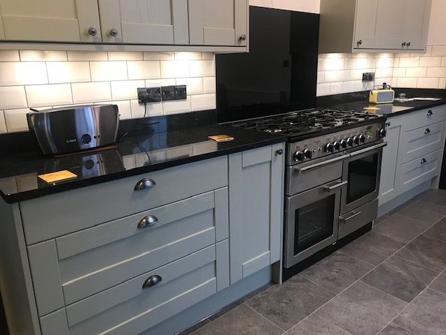 a kitchen with white cabinets and black counter tops, an oven and microwave in it