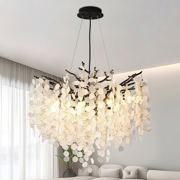 a large chandelier hanging from the ceiling in a living room with white furniture