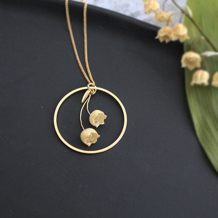 ＊material lily of the valley. (dried flowers or preserved flowers coated UV resin), ＊gold plated necklace ＊free shipping worldwide for all orders.(from Japan) Thank you for viewing! ＊ ＊ ＊ ＊ ＊   return of happiness 花言葉は『再び幸せが訪れる』 わたしの大好きな花、本物のすずらんの花でつくった、 キャンドルの灯りをイメージしたネックレスです。 ろうそくの灯りのような金色の環が、 どこか暖かみを感じさせるデザインです。 アイボリー色の優しい雰囲気と、ペールゴールドの装飾が、 落ち着きがあって上品ながら、 大きめのフープの存在感が、シンプルな服装にとても映えます。 おそろいのピアスもあります。 毎年、お庭に咲いた繊細なすずらんを、 壊れないように、ひとつひとつ丁寧にドライフラワーに仕上げ、 樹脂で厚くコーティングしています。 花びらの葉脈が透けてみえるので、 既製品のビーズにはない、ふしぎな「本物のお花感」があります。 ＊ 高原にひっそりと咲くすずらん。 恥ずかしそうにうつむいた その控えめな姿は、 目立ちませんが、そんなすずらんの愛おしさをそのままに、 女性らしい落ち着いた雰囲気のネックレスに仕立ててみました。 すずらんシリーズは、イベントでも一番人気の作品です。 アイボリー×ゴールドの色調で、 季節を問わずお使いいただけるのも、おすすめポイントです。 サイズ感：30mm（フープ部分）、チェーン40cm+アジャスター5cm 耳もとですずらんが揺れるようすは、りんりんと音がしてきそうなかわいさです。 ▼instagramで揺れるようすの動画を見られます。参考にどうぞ。 Nature-inspired Gold Flower Pendant Necklace, Gold Dainty Flower Necklace With Pressed Flowers, Dainty Gold Flower Necklace With Pressed Flowers, Gold Flower Necklace With Pressed Flowers In Round Pendant, Delicate Gold Necklace With Pressed Flowers, Delicate Gold Birth Flower Necklace, Gold Botanical Necklace With Flower Charm, Nature-inspired Gold Necklace With Pressed Flowers, Lily Of The Valley Necklace