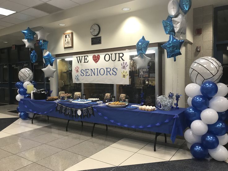 a table with blue and white balloons in front of a sign that says we love our seniors