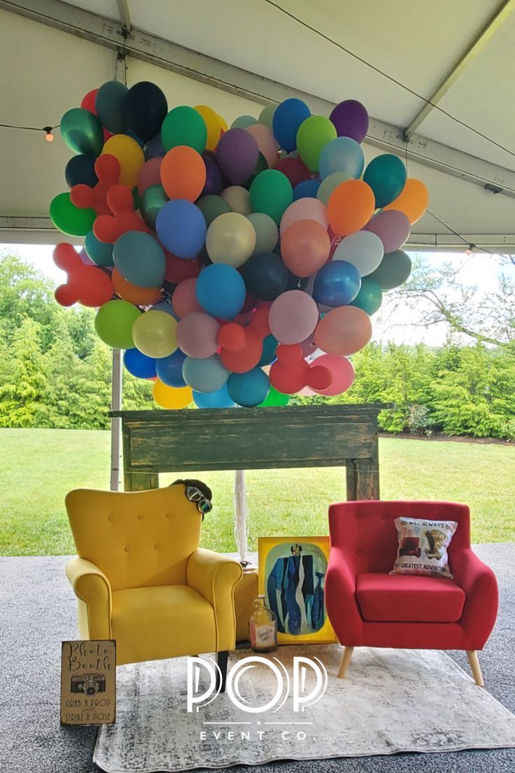 two chairs and a couch under a canopy with balloons hanging from it's ceiling