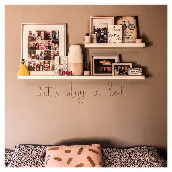 there are pictures on the wall above the bed and below it is a shelf that says, let's stay in bed