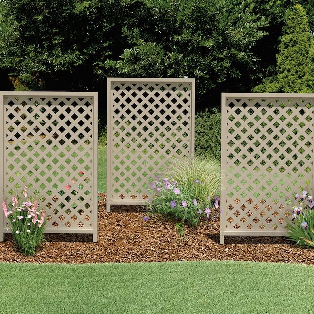 three wooden privacy screens in the middle of a flower garden with grass and flowers around them