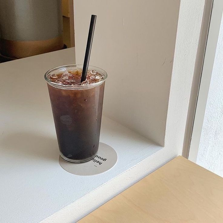 a drink sitting on top of a counter next to a mirror with a black straw in it