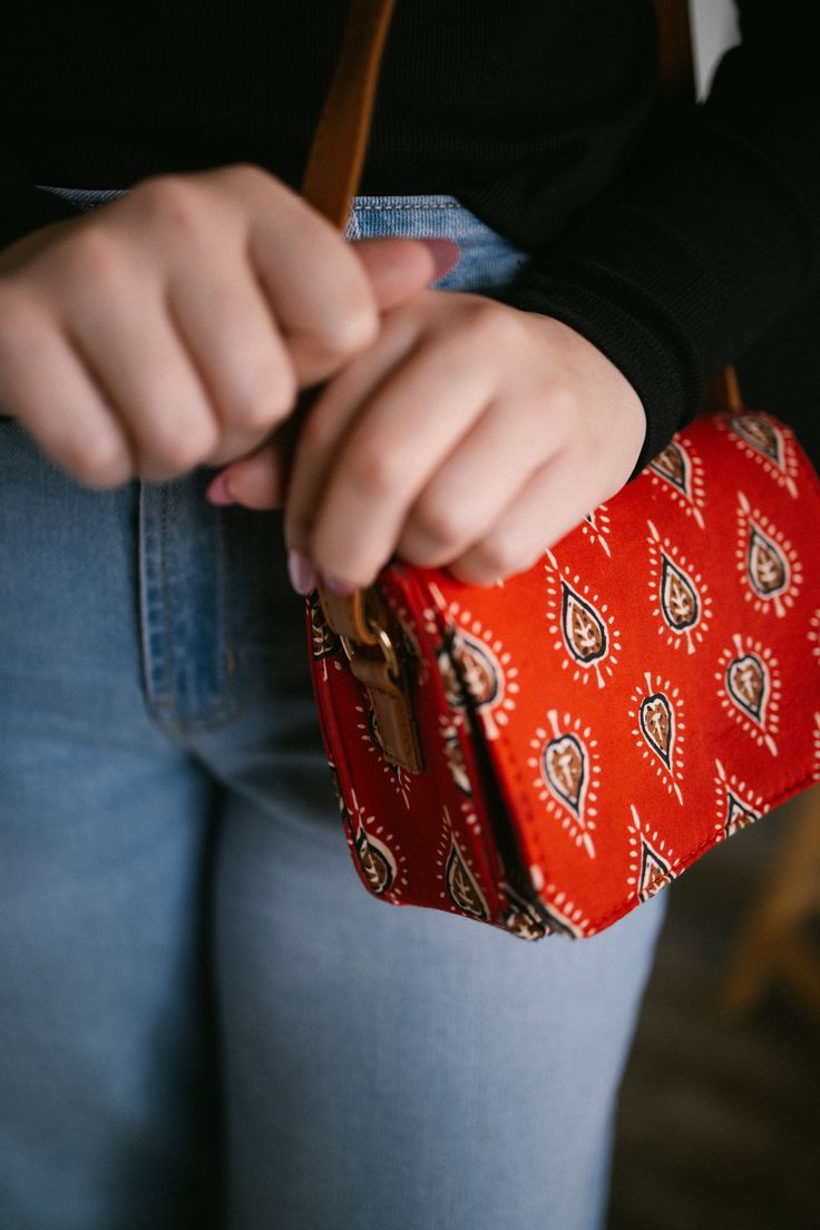 This box sling bag is perfect for carrying just the essentials, in style. Details: -7"L x 3"W x 5.25"H -Made with a Indian cotton fabric -magnetic, snap close front flap -vegan leather, cognac colored, adjustable strap (up to 42") -Lined interior -1 interior pocket Casual Red Shoulder Box Bag, Red Square Satchel As Gift, Red Square Satchel For Gift, Red Square Satchel Gift, Red Square Flap Bag For Everyday, Casual Rectangular Clutch For Gift, Rectangular Bag With Snap Closure As Gift, Red Rectangular Box Bag For Everyday Use, Rectangular Shoulder Bag With Magnetic Closure As Gift