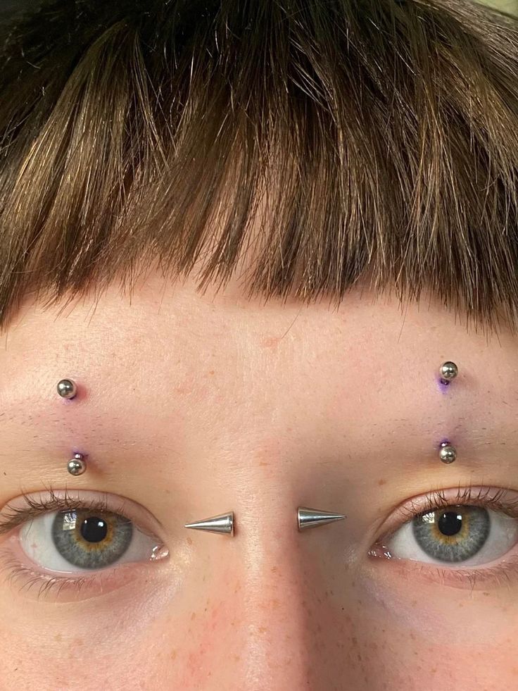 a close up of a person with piercings on their forehead