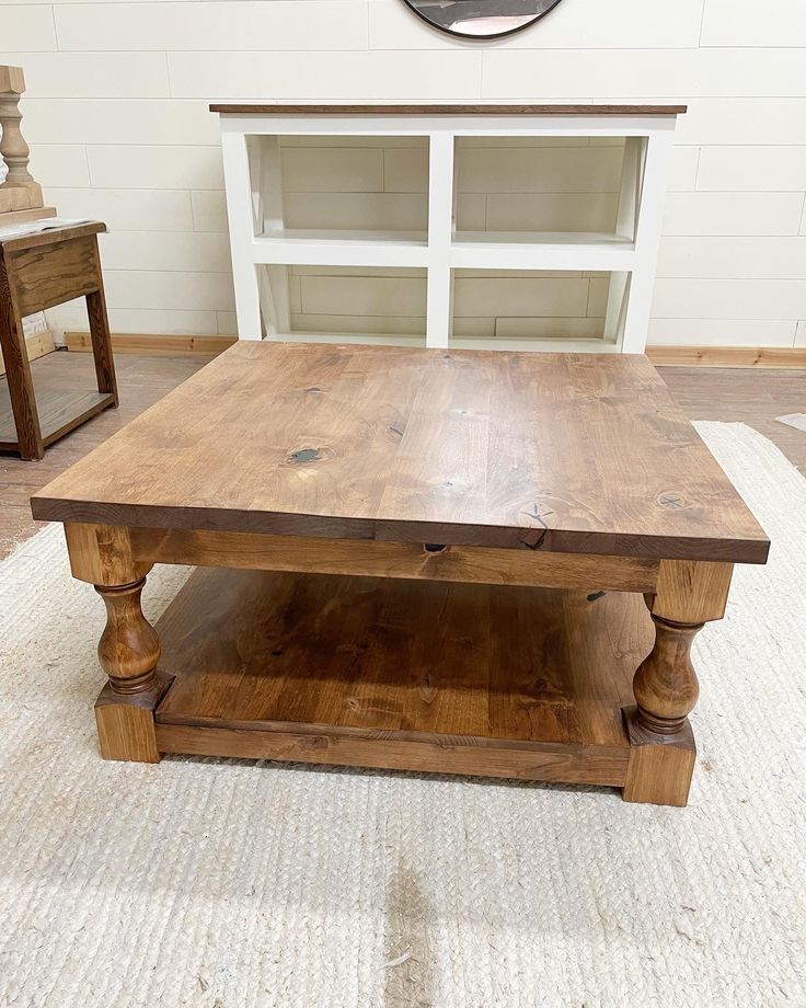 a wooden coffee table sitting on top of a rug in front of a white wall