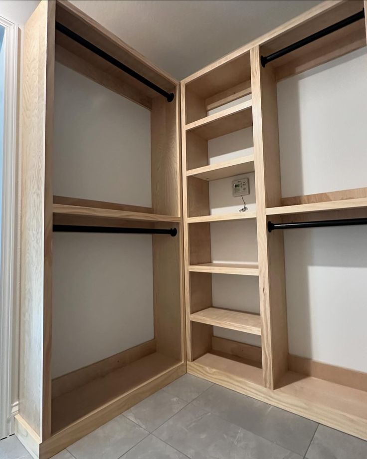 an empty walk in closet is shown with shelves and doors open to reveal the bathroom