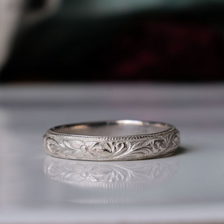 Beautifully hand engraved with flourishes, flowers and skulls, this ring is perfect as a stack ring, a wedding band, or simply on its own.  Made in 100% recycled sterling silver This ring has been made entirely by hand in Charlie's London workshop. Each piece is made to order, so please allow 2 - 3 weeks for production. Materials: Sterling silver Measurements: 4mm wide band White Gold Engraved Ring With Decorative Band For Promise, Promise Engraved Ring In White Gold With Decorative Band, Elegant Stamped White Gold Engraved Ring, Heirloom White Gold Engraved Promise Ring, Engraved Promise Ring With Decorative Round Band, Promise Engraved Ring With Decorative Band, Heirloom White Gold Stamped Rings, Classic Engraved Ring With Decorative Band For Promise, Heirloom Style Engraved White Gold Rings