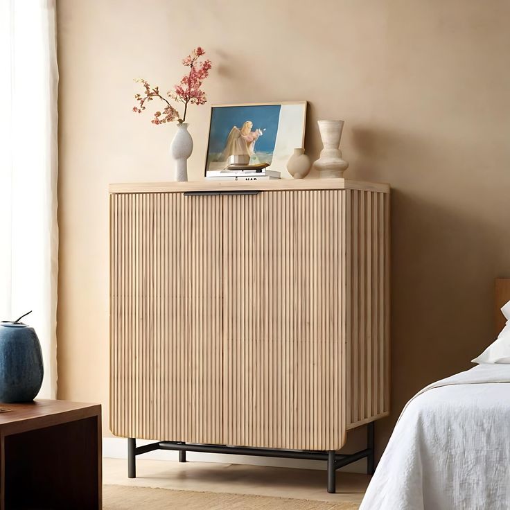 a room with a bed and a wooden cabinet next to a vase on a table