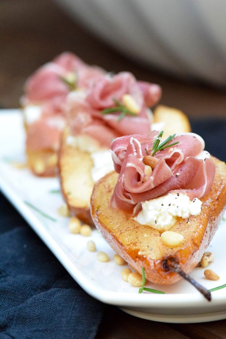 two pieces of bread with meat and vegetables on it sitting on a white platter