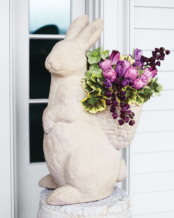 a statue of a rabbit with flowers in it's mouth sitting next to a door