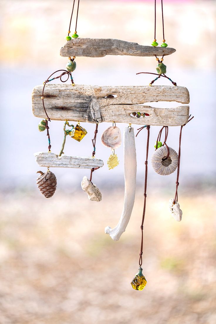 a wind chime hanging from the side of a wooden pole with shells and seashells on it