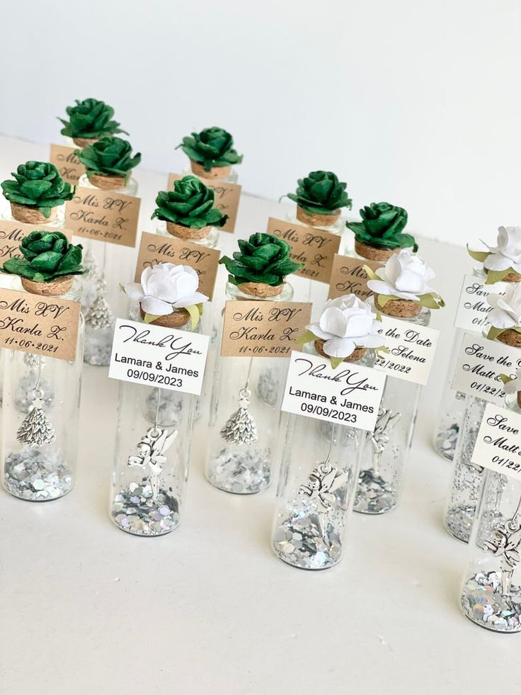 there are many small glass vases with plants in them on the table, and each has a name tag attached to it