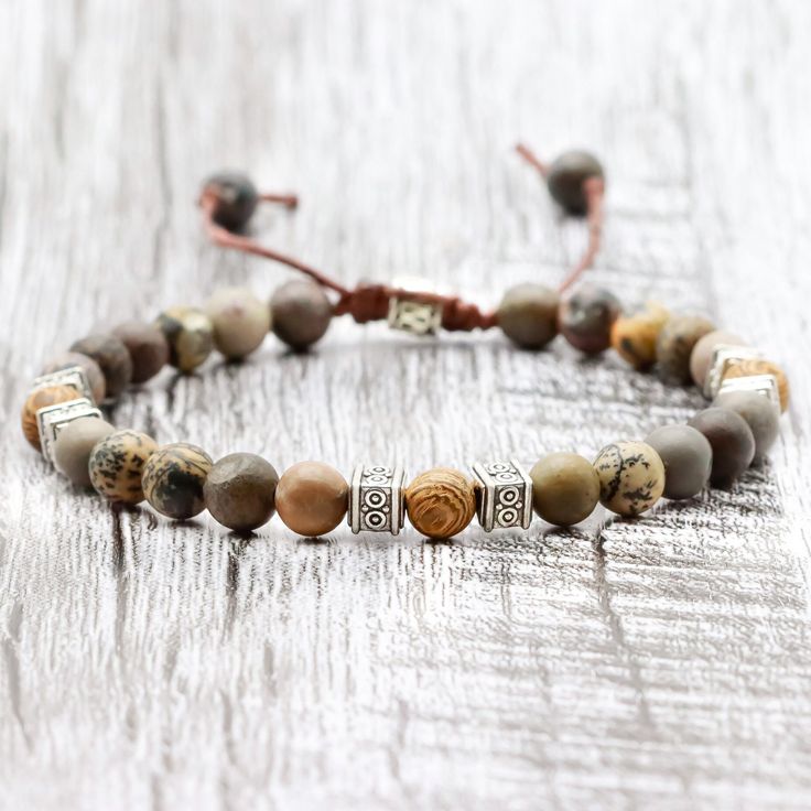 ◈ This beautiful Tibetan bracelet is carefully handcrafted with jasper rhodonite beads and high quality wooden beads. Each bead has been individually selected to ensure beauty and durability. This handcrafted men's bracelet is a versatile accessory that can complement any outfit. The wooden beads used in this bracelet have a rustic, natural charm. Each has a unique pattern and texture, making each bracelet a special and unique piece. These beads are strung on sturdy thread that has been skillful Adjustable Brown Polished Beaded Bracelets, Jasper Beaded Bracelets For Gifts, Brown Jasper Round Bead Bracelets, Brown Jasper Bracelets With Round Beads, Earthy Jasper Round Bead Bracelets, Adjustable Brown Polished Bead Bracelets, Earthy Jasper Gemstone Bead Bracelets, Adjustable Beaded Nature-inspired Bracelet, Handmade Earthy Jasper Bracelets