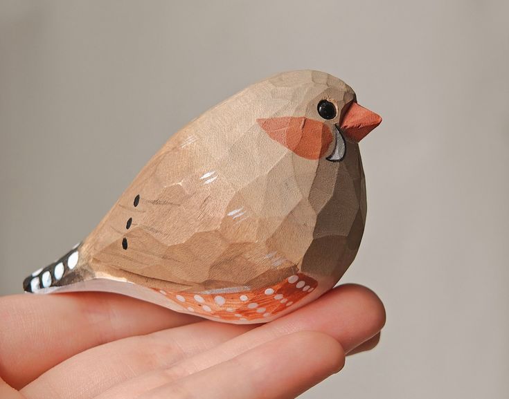 a small wooden bird sitting on top of someone's hand