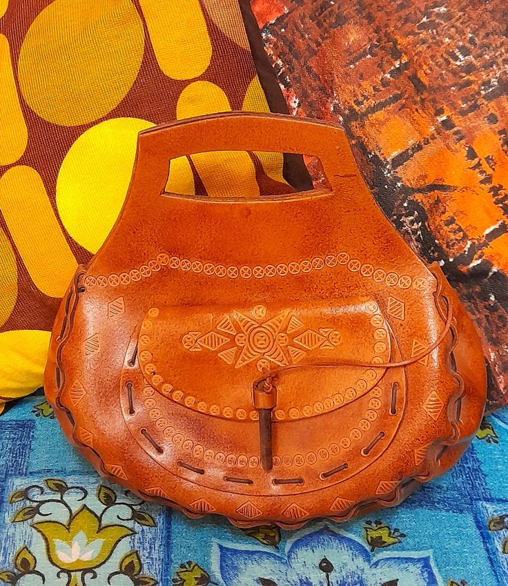 "70's handmade tooled leather bag🧡 Perfect for any lover of 70's boho style!🧡 Handmade, tooled leather with a lovely embossed pattern. Grab handle... lovely curved chunky design...handstitched with leather thonging...sweet pocket on the front..the flap closes with a loop and a length on bamboo (which is attached to a cord so you don't lose it)... Main bag closes with 2 hidden poppers🧡 Lovely vintage condition..only light wear🧡 🧡🧡MEASURES🧡🧡 12\" wide x 11\" tall to top of handles  x 4\" d Bohemian Brown Hand-tooled Shoulder Bag, Hippie Brown Leather Bag, Hippie Brown Shoulder Bag For Daily Use, Brown Hippie Shoulder Bag For Daily Use, Bohemian Brown Hand-stitched Bags, Bohemian Hand Tooled Leather Shoulder Bag, Bohemian Hand Tooled Brown Bag, Brown Leather Hippie Bag, Bohemian Hand-tooled Brown Bag