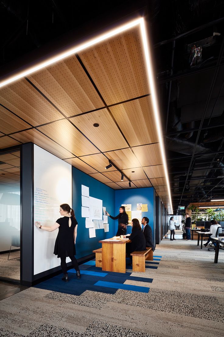 people are standing in an office area with blue walls and white board on the wall