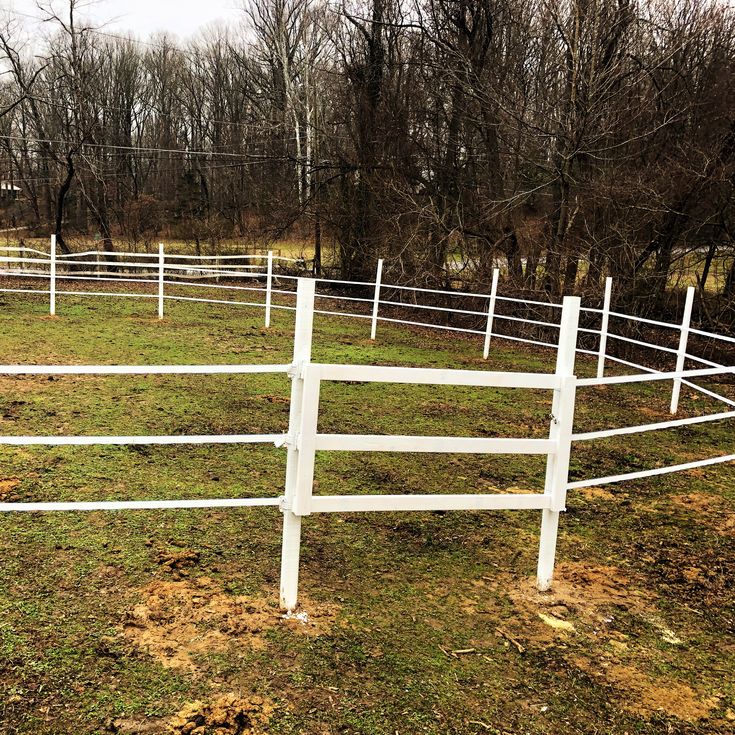 a white fence in the middle of a grassy field