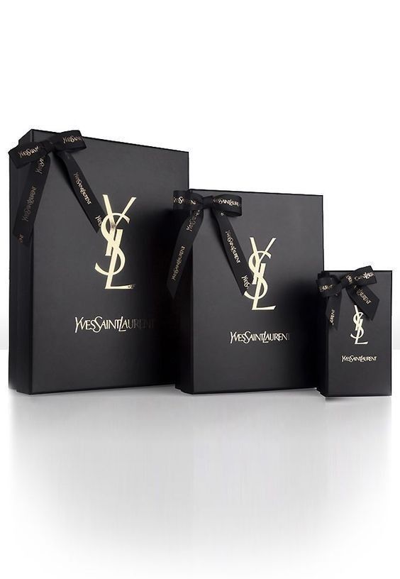 three black shopping bags with gold logo on the front and bottom, tied together in a bow