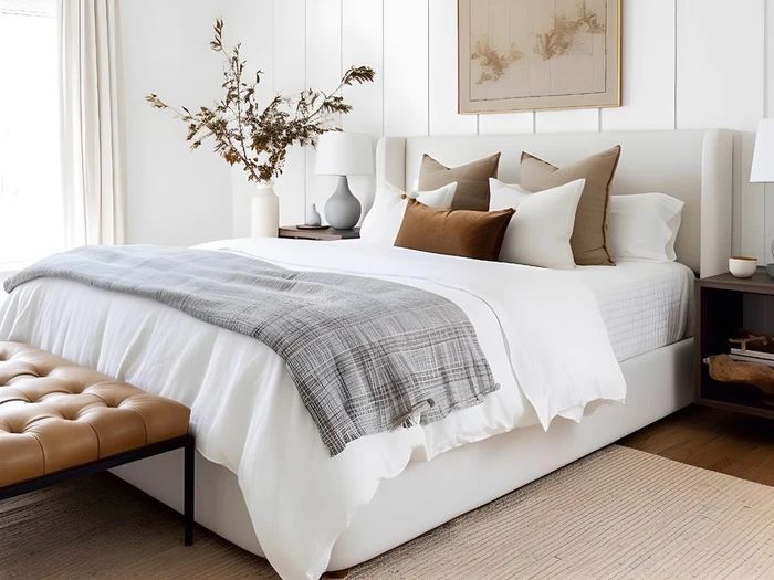 a bed with white sheets and pillows in a bedroom