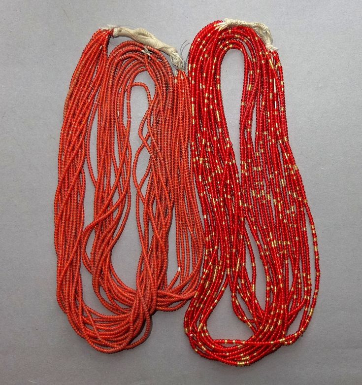 two red string necklaces with gold dots on them, sitting next to each other