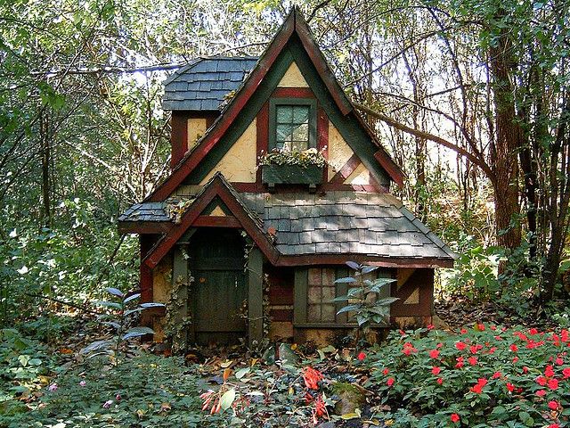 a small house in the woods surrounded by flowers