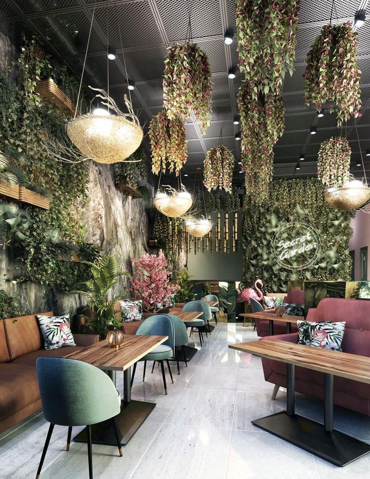 the interior of a restaurant with plants hanging from the ceiling and wooden tables in front of them