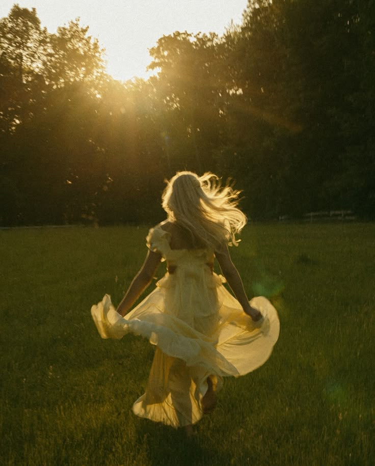 a woman in a white dress is running through the grass with her hair blowing in the wind