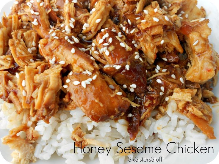 a white plate topped with rice covered in chicken and sesame seed flakes on top of it