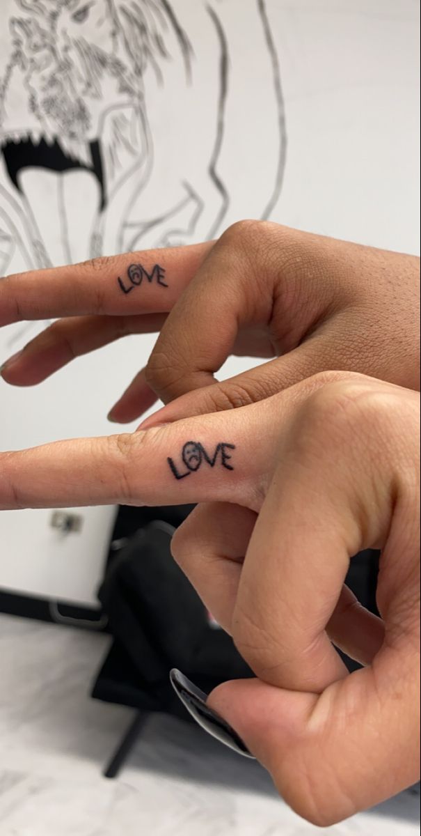 two fingers with the word love written on them and one hand holding another's finger