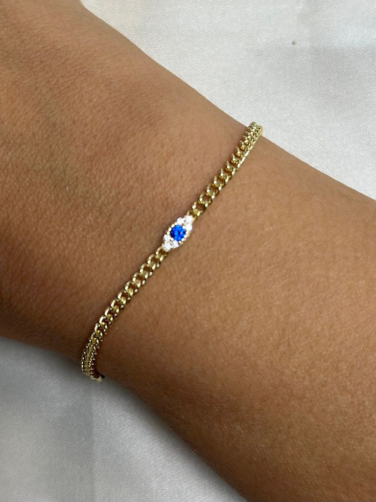 Introducing our small evil eye bracelet, a stunning piece that exudes elegance and charm. This delicate gold bracelet boasts a central ornament showcasing a captivating blue gemstone, encircled by a cluster of dazzling white stones, reminiscent of diamonds. The simplistic design enhances the bracelet's overall allure, making it a must-have accessory for those who appreciate subtle sophistication. -- Material: Solid Sterling Silver, 14k Gold Plated -- Stones: white cubic zirconias -- Color: Silver / Gold -- All of our products are handcrafted ---------------------------------- Merchandise images are enlarged to show detail and may not always be exactly as pictured. Due to the nature of this item being handmade, each piece is unique. Elegant Evil Eye Bracelet With Adjustable Chain, Elegant Gold Evil Eye Bracelet With Diamond Eyes, Elegant Gold Evil Eye Bracelet With Diamond Details, Elegant Gold Evil Eye Bracelet With Cubic Zirconia, Elegant Round Chain Bracelet With Evil Eye, Elegant Round Evil Eye Chain Bracelet, Elegant Gold Plated Evil Eye Bracelet, Elegant Evil Eye Bangle Jewelry, Elegant Evil Eye Chain Bracelet