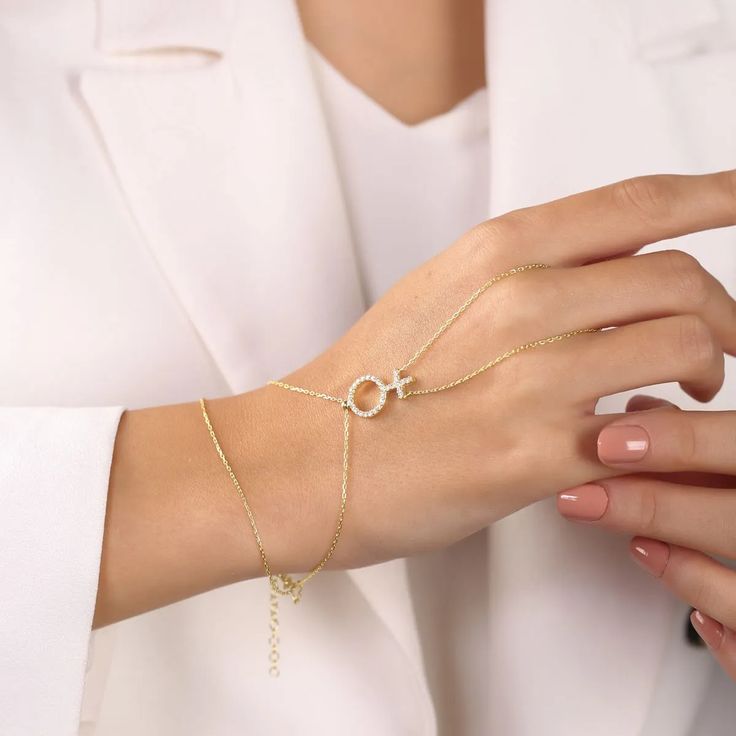 This playful piece, featuring the iconic Venus symbol, is perfect for celebrating love and pride. Whether you’re dressing up for a night out or adding a touch of sparkle to your everyday look, this hand chain is sure to turn heads and start conversations. Ready to shine and show off your pride? 🌈✨ Metal: 925 sterling silver Finish: 18k gold Gemstone: white zirconia Bracelet length: adjustable with 4 cm extender (1.5") Chain: cable link Clasp: spring ring Hypoallergenic, anti-tarnish, nickel-free Don’t forget, proper care of your gold-plated jewelry will preserve its appearance for a long time. Keep it shining bright by using the soft side of the provided JFW polishing cloth Elegant Clavicle Chain Body Jewelry, Gold Dainty Body Jewelry For Party, Delicate Chain Body Jewelry For Wedding, Metal Body Jewelry For Wedding, Adjustable Clavicle Chain Body Jewelry Gift, Metal Body Jewelry For Party, Gold Clavicle Chain Body Jewelry As Gift, Sterling Silver Body Jewelry With Adjustable Chain For Party, Trendy Adjustable Body Jewelry