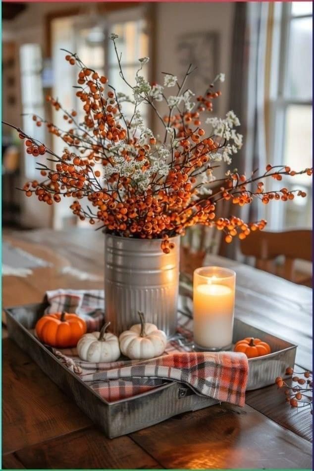 an arrangement of flowers, candles and pumpkins in a tin can on a table