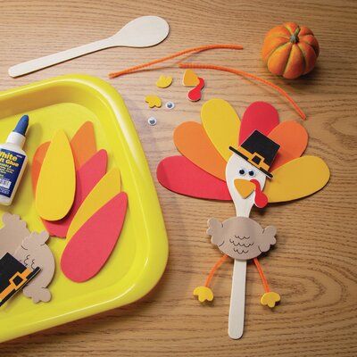 paper turkeys and other thanksgiving crafts on a table with spoons, fork and glue