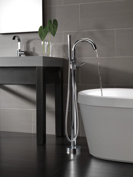 a white tub sitting next to a sink in a bathroom under a mirror with a flower on it