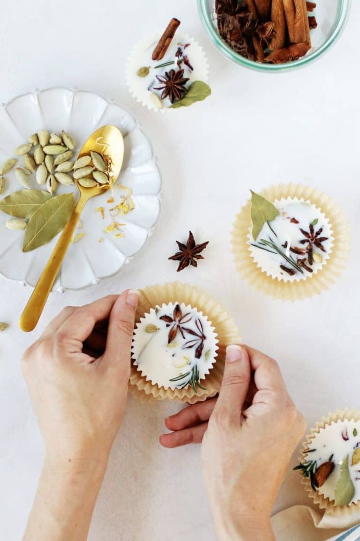 two hands are decorating cupcakes with cinnamon and star anise